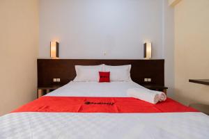 a bedroom with a large bed with a red blanket at RedDoorz at Omahku Guest House Batu in Malang