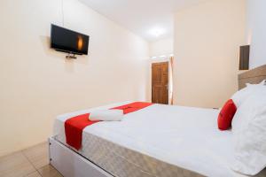 a bedroom with a bed with a tv on the wall at RedDoorz at Omahku Guest House Batu in Malang +10 photos