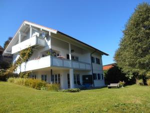 a white house with a balcony and a grass field at Ferienwohnung Rath in Oberreute