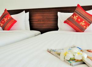 two beds with red and white pillows and a book at Family House Zen Boutique Resort in Pai
