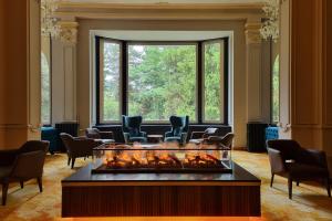 a room with a fireplace and chairs and a large window at Hotel Reine Victoria in St. Moritz