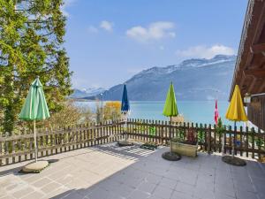 a patio with umbrellas and a fence next to a lake at Hotel Wildbach Brienz - Self Check-in in Brienz