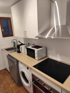 a kitchen with a washing machine and a microwave at Appart proche gare centre ville bureau parking in La Loupe