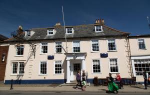 a group of people walking in front of a white building at Crown Hotel in Southwold