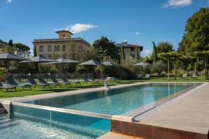 a swimming pool with chairs and umbrellas at Hotel Palazzo San Lorenzo & Spa in Colle di Val d'Elsa