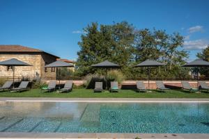 a swimming pool with lounge chairs and umbrellas at Hotel Palazzo San Lorenzo & Spa in Colle di Val d'Elsa