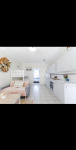a living room with a couch and a kitchen at Top Location Beachside Apartment in Cronulla
