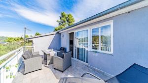 a blue house with a balcony with chairs and a table at Apartman Roza 2 by Villas Guide in Vela Luka