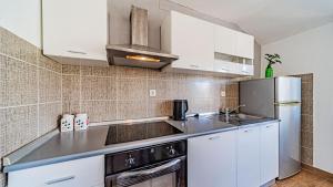a kitchen with white cabinets and a stainless steel refrigerator at Apartman Roza 2 by Villas Guide in Vela Luka