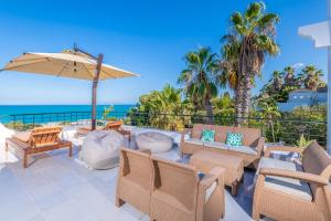 a patio with chairs and an umbrella and the ocean at Villa Verde Azura in Bin Rhilouf