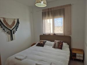 a bedroom with a white bed with a window at נחת רוח Nachat Ruach in Mitzpe Ramon