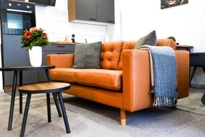 an orange couch in a kitchen with two tables at Apart4me Style Apartment Geislingen zentral mit Parkplatz in Geislingen an der Steige