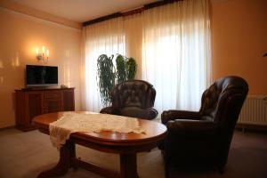 a living room with two chairs and a table and a tv at Roskosz Zespół Dworsko Parkowy in Biała Podlaska