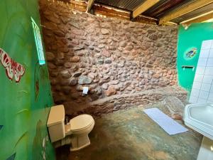 a stone bathroom with a toilet and a sink at Backpackers at Kanaan in Hazyview