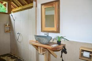 a bathroom with a bowl sink on a wooden counter at Beda gaya ecolodge Rangsot 2 in Tanjung