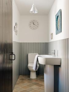 a bathroom with a toilet and a sink and a clock at New Haven in Elie +34 photos