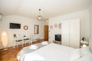 a white bedroom with a bed and a desk at Guests house DaLi in Rovinj +6 photos