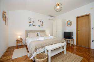 a white bedroom with a bed and a tv at Guests house DaLi in Rovinj