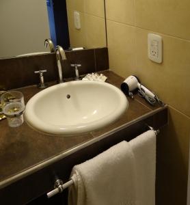 uma casa de banho com um lavatório branco e toalhas num balcão em Departamentos Las Cañas em Mendoza