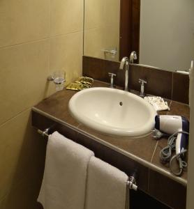 y baño con lavabo, espejo y toallas. en Departamentos Las Cañas en Mendoza
