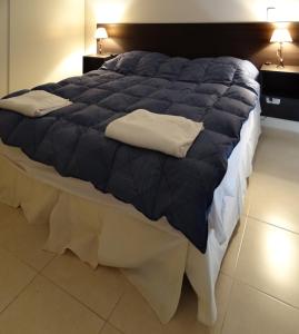 a large bed with a blue comforter and white sheets at Departamentos Las Cañas in Mendoza