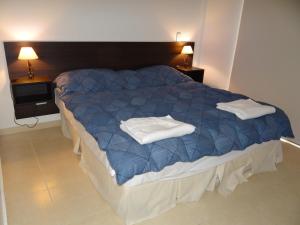 a bedroom with a blue bed with two towels on it at Departamentos Las Cañas in Mendoza