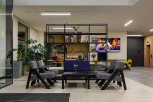a lobby with chairs and tables and a tv at TULIP Residences Lviv in Lviv
