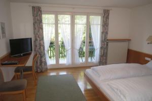 a bedroom with a bed and a desk and a window at Gästehaus Frohe Aussicht in Kressbronn am Bodensee