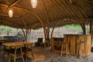 a restaurant with tables and chairs under a straw roof at Beda gaya ecolodge Rangsot 2 in Tanjung