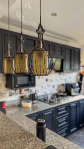 a kitchen with blue cabinets and three hanging lights at Hide Out Lake Villa Uganda in Bwerenga