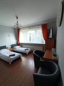 a living room with two beds and a couch and chairs at Hotelik -Świerki in Swarzędz