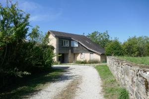 a house on a dirt road next to a stone wall at La Mondee in Badefols-dʼAns