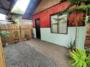 a house with a red wall and a door at Charming Urban Hideout in Puerto Princesa City