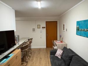 a living room with a couch and a kitchen at Ipê Rosa Apartamento in Brasília