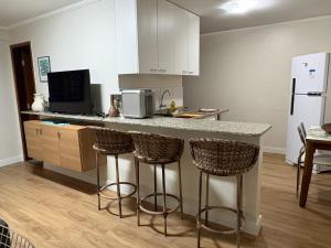 a kitchen with a counter with bar stools and a microwave at Ipê Rosa Apartamento in Brasília