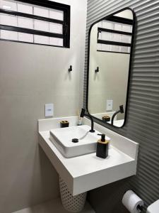 a bathroom with a white sink and a mirror at Ipê Rosa Apartamento in Brasília +19 photos