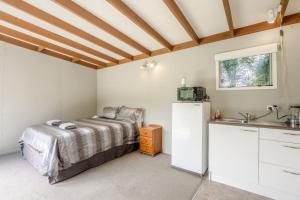 a bedroom with a bed and a sink at Stoneybrook Cabins in Waimauku