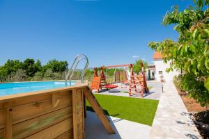 a backyard with a pool and a playground at Nika Vacation House in Zavojane