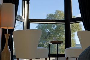 a room with white chairs and a table and windows at The Tall Trees Hotel in Amlwch