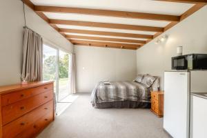 a bedroom with a bed and a refrigerator at Stoneybrook Cabins in Waimauku