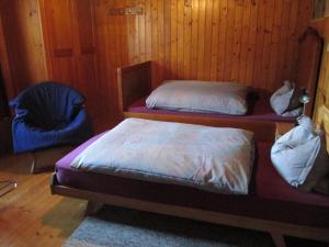 two beds and a chair in a room with wooden walls at B&B Am Büel in Sevelen