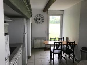 a kitchen with a table and chairs and a clock on the wall at Longère 6-8 personnes - L'Ecrin Vert in Loison-sur-Créquoise