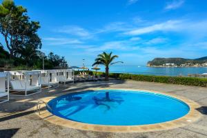 a swimming pool with chairs and the ocean in the background at Hotel Vibra Beverly Playa in Paguera