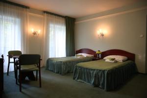a hotel room with two beds and a table at Roskosz Zespół Dworsko Parkowy in Biała Podlaska