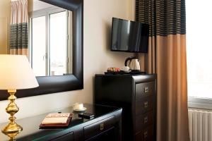 une chambre d'hôtel avec une télévision et une commode avec une lampe dans l'établissement Hotel Aguado, à Dieppe