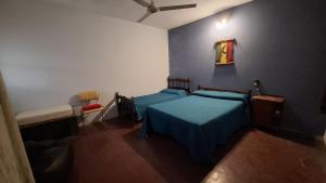 a bedroom with a bed with a blue bedspread at Casa en Claromecó in Balneario Claromecó