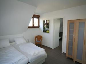 ein Schlafzimmer mit einem weißen Bett und einem Stuhl in der Unterkunft Café Perlmuschel in Iznang