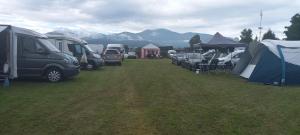 a group of vehicles parked in a field with tents at Camping Dorfer in Spielberg +6 photos