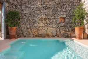 a large blue swimming pool in front of a stone wall at Masseria De Li Travaj - Rive del Salento in Patù