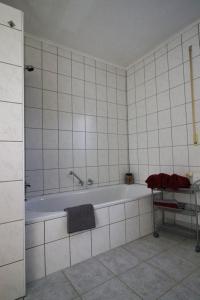 a white tiled bathroom with a tub in it at Haus Hönigblick in Wilnsdorf +4 photos